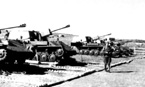 В расположении лагеря 958-го самоходного артполка, который был оснащен новыми СУ-76М послевоенной (1945 года) модификации. Тактические обозначения ("6") и номера ("23814") САУ нанесены на задней части рубки. Фото 131 показывает как командир 159 сд 5А генерал-майор Н.В. Калинин слушает доклад о выполнении боевой задачи. Маньчжурия, сентябрь 1945 года.
