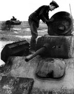 Немецкий солдат осматривает подбитый советский танк Т-70М. Машина имеет антенну, установленную на кормовом листе башни. Обращает на себя внимание пробоина в нижней части люка механика-водителя. Осень 1943 года.