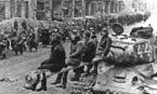 Советские танкисты, сидя на стволе тяжёлого танка ИС-2, наблюдают за прохождением колонн немецких пленных. Берлин, май 1945 года.