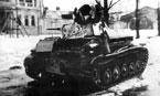 Немецкий солдат осматривает подбитый на улице одного из населённых пунктов лёгкий танк Т-70М. Машина имеет зимний камуфляж, бортовой номер 345 и надпись "Москва" на башне. Март 1943 года.